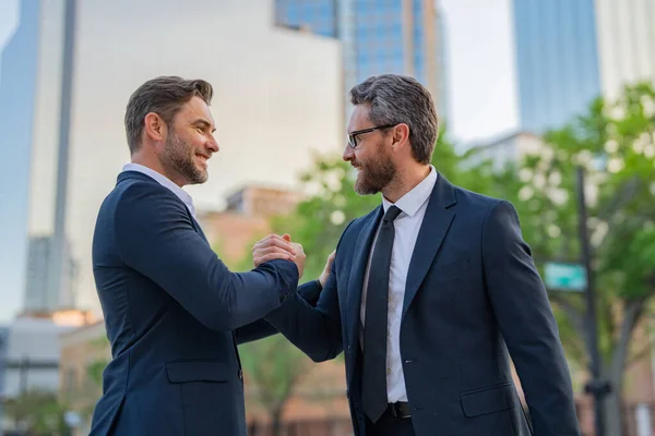 The two business team worked together to achieve their goals. Business man shaking hands. Two businessmen handshake outdoor. Handshake business people