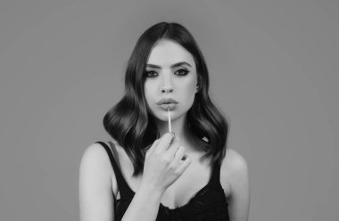 Makyajlı, izole edilmiş stüdyo geçmişi olan güzel bir kız yüzü. Moda ve güzellik, makyaj, kozmetik. Genç bir kadın dudaklarına ruj sürüyor.