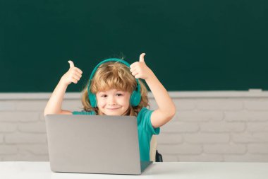 Zeki bir okul öğrencisi, güzel bir öğrenci dizüstü bilgisayara kulaklık takıyor, müzik dersi bilgisayarı kullanıyor. Video çağrısı, uzaktan öğretmenle e-çalışma. Okuldaki ilk günüm.