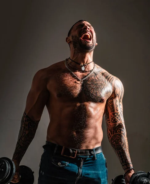筋肉の男を叫んで ダンベルと運動する興奮した筋肉の男 裸の胴を持つスポーティフック 強みと動機 — ストック写真