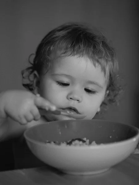 厨房里有趣的小宝宝用手指从盘子里吃东西 — 图库照片