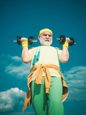 Kıdemli sporcu dambılları kaldırıyor. Yaşlılık sağlığını gevşetmek için bir bahane değildir. Yaşlı adam egzersizi.