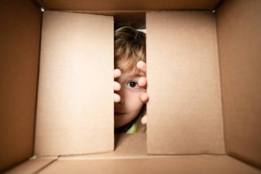 Karton kutulu mutlu çocuk, internet mağazasından paketleri açıyor. Çocuk müşteriler hızlı teslimat hizmetinden memnun. Kutusu açık bir çocuk. Gözlerini kapat ve bak.