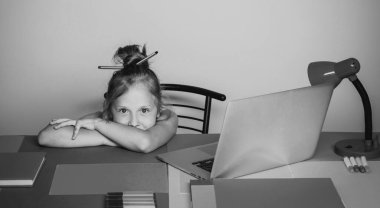 Anaokulu öğrencisi. Eğitim ve erken kalkınma kavramı. Amerikalı kız dizüstü bilgisayar ve kitaplarla notlar yazıyor.