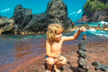 Çakıl taşı yapan tatlı çocuk deniz kıyısındaki volkanik bir kayanın üzerine yığılmış. Zen kavramı