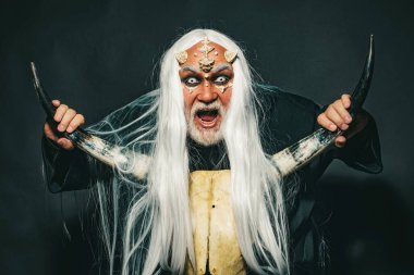 Drakula - Cadılar Bayramı konsepti. Kötü vampir adam. Sihir ve masal kavramı. Beyaz gözlü bir vampir adam. Şeytani iblisleri yakmak kötü güçleri çağırır ve cehennemi açar. Yaşlı adam iki kırmızı boynuz tutuyor.