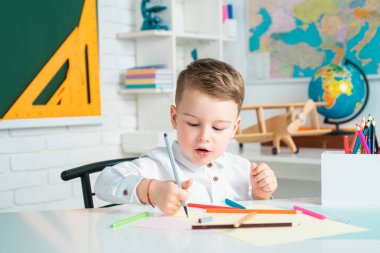 Çocuk sınıfta yazı yazıyor. İlkokulun çocuğu