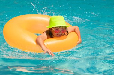 Çocuk havuzda yüzüyor. Çocukla yaz tatilinde su sporu aktivitesi. Yaz gezisi