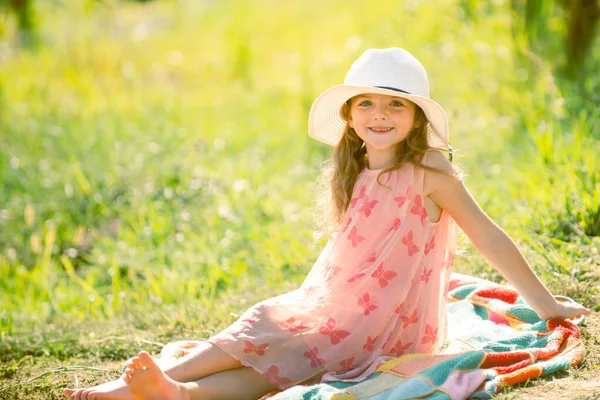 少女は夏の公園の緑の草の上に座っている 面白い子供たちの屋外クローズアップ肖像画が直面しています 夏の子供屋外の肖像画 かわいい子供の顔を閉じてください 夏の日に楽しい屋外を持っている子供 — ストック写真
