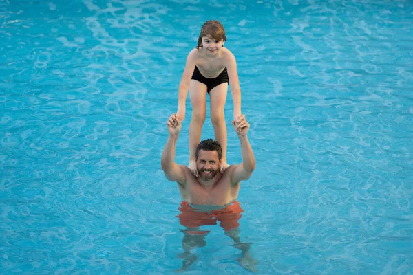 父子俩在游泳池里游泳 夏之家常周而复始 父亲和儿子在暑假全家度假 父亲和儿子在游泳池里休息 在游泳池里的家人爸爸在游泳池里游泳的孩子 — 图库照片