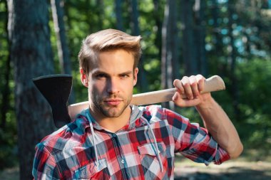 Ciddi yüzdeki oduncu omzunda balta taşıyor.