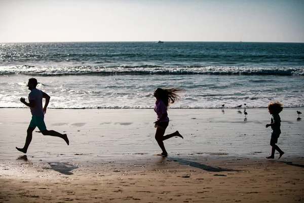 海の近くを走るフィットネスファミリーのシルエット 子供と屋外フィットネスのためのスポーツのための家族のジョギング — ストック写真