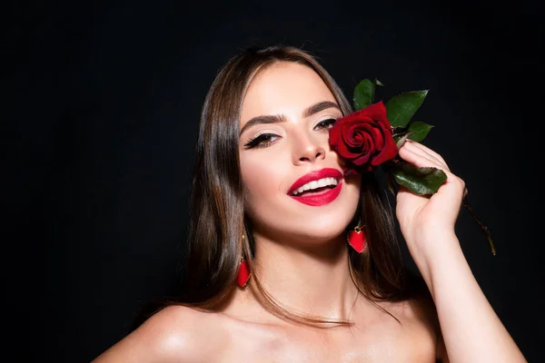 黒を背景に赤いバラを持つ若い美しいセクシーな女性のクローズアップ肖像画 閉じます新鮮な顔の女の子 — ストック写真