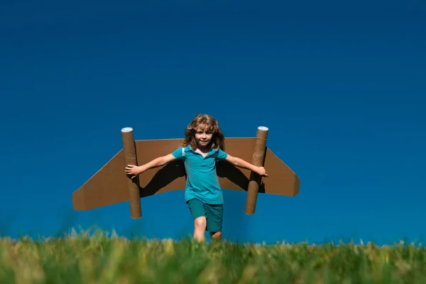 Kid with jet pack superhero. Child pilot against summer sky background. Boy with paper plane flight, toy airplane with cardboard wings, Imagination, kids freedom