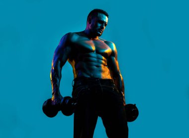 Kaslı adam dambıllarla egzersiz yapar. Seksi çocuk.