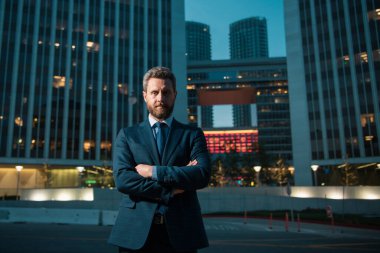 Ofisin dışında duran kendinden emin bir iş adamının portresi. İş yerinin dışında kolları kavuşturulmuş gülümseyen iş adamı CEO 'su. İyi giyimli iş adamı.