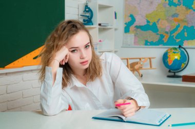 Ergen öğrenci. Kitaplarla otururken not alan düşünceli bir genç kızın portresi.