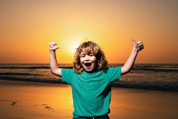 日没のビーチで子供の男の子 手を挙げた 驚くべき子供の感情 — ストック写真