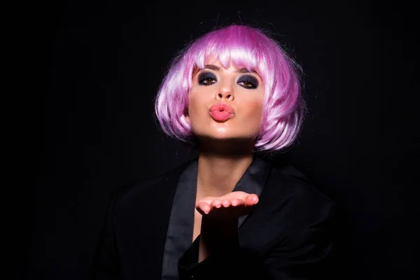 Beautiful air kiss of beauty model, fashionable pink wigs. Photo of young beautiful woman with pink wig isolated on black background