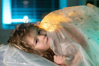 Büyük yatakta yatan küçük bir çocuğun portresi. Mutlu çocuklar iyi geceler diliyor. Çocuk yatakta uykulu.