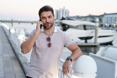 Şehir caddesinde telefonda konuşan yakışıklı bir adam. Büyük şehirde şehir hayatı yaşayan başarılı bir erkek model telefonda konuşuyor. Genç erkek manken dışarıda telefon kullanıyor. İş telefonu görüşmesi