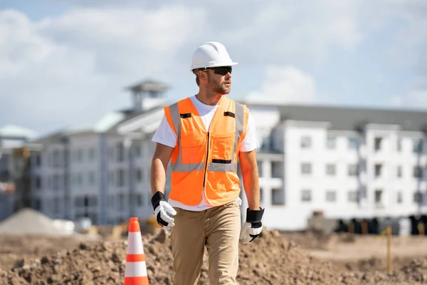 建筑工人戴着硬礼帽在工地进行建筑工程 建筑工地附近一名戴头盔的建筑工人 工作上的奠基人 建筑工地上戴头盔的男工 — 图库照片