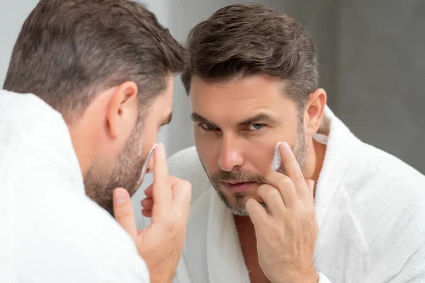 美容クリームを顔に塗る熟年男性 顔の治療 顔クリームを適用男の美しさの肖像画 スキンケア製品 しわの顔の皮膚のための保湿クリーム 完璧な肌 朝のルーチン — ストック写真