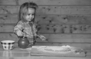 Pişirme bebek. Çocuk mutfakta yemek pişiriyor. Küçük çocuk hamuru un ile oynayan bir tencereye koyar.