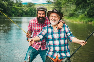 Sinek balıkçılık ve düzenli balıkçılık arasındaki fark. Mutlu baba ve oğul birlikte yaz gününde nehirde güzel gökyüzü altında balıkçılık