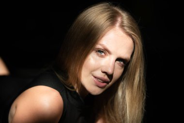 Gri arka planda şık seksi bir kadın. Siyah stüdyoda genç ve şehvetli bir model. Sarışın kız yüzünü kapat. Gölgedeki zarif kadının moda portresi.