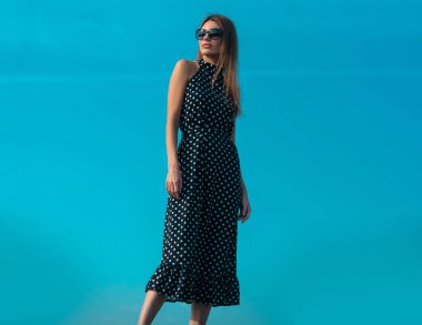 Moda kadını dışarıda poz veriyor. Seksi elbiseli çekici genç kadın yazın tadını çıkarıyor.