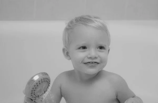 面白いかわいい赤ちゃんはお風呂で泡で泳いでいます かわいい小さな赤ちゃん男の子入浴白日当たりの良い浴室で泡とアヒルのおもちゃで遊んで — ストック写真