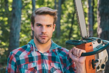 Ormanın yakınında baltaile yakışıklı genç adam - portre kadar yakın. Oduncu ormanda çalışıyor. Günlüğü. Yenilenebilir bir enerji kaynağı olarak yakacak odun. Kereste fabrikasında testere ile oduncu
