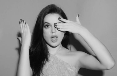 Kadın elleriyle gözlerini kapatıyor. Kırmızı manikür. Şaşırmış genç bir kadının şok olmuş yüzü. El sallayan heyecanlı kadın portresi. Şaşırtıcı bir şekilde ağzını açtın.