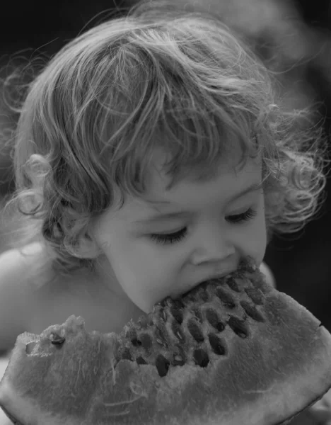 幸せな子供スイカを食べる 子供の赤ちゃんは庭でスイカを食べ 顔を閉じます 子供は屋外で果物を食べる 子供の赤ちゃんは庭でスイカのスライスをかむ演奏 — ストック写真