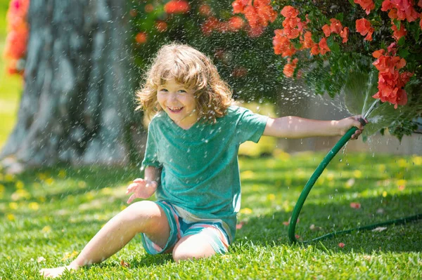 庭で遊んでいる子供は ホースから注ぐと雨が降ります 幸せな子供時代のコンセプト — ストック写真