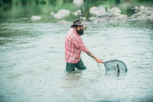 渔夫在山河里用钓竿钓鱼 一个放飞的渔夫在森林里的河里钓野生鳟鱼 用网捕鳟鱼 — 图库照片
