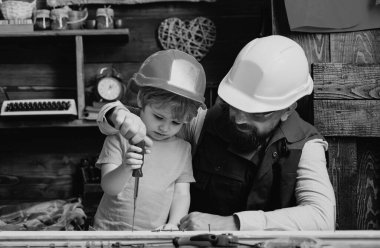 Baba oğluna tornavida ve vida kullanmayı öğretiyor.