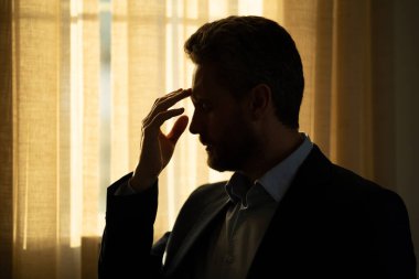 Yorgun adam acı çekiyor. Stresli bir adamın portresi ofiste baş ağrısından muzdarip. Stresli bir iş. Ağrılı bir adamın ağrıdan dolayı migreni tutar. Stresli, baş ağrısından yorgun bir adam.