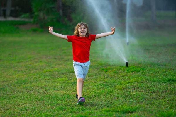 夏の庭で子供が遊ぶ 草水をやる 緑の公園の散水芝生の自動散水灌漑システム スプリンクラー水をやる 子供の園芸の概念 小さな子供は水噴霧を楽しんでいます — ストック写真