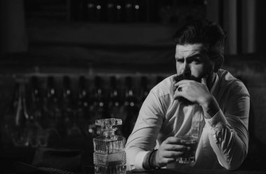 Yakışıklı sakallı bir iş adamının portresi zarif bir takım elbise içinde viski içiyor.