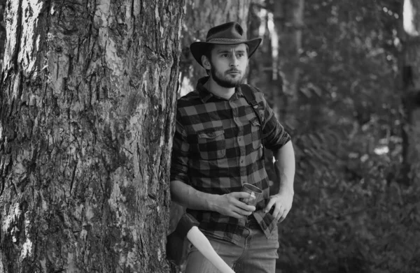 森の背景に斧を持つ木材ジャック 男の仕事をしている人 あごひげを生やしたハンサムな若者が木を運ぶ 木材ジャックのようなポーズのスタイリッシュな若者 — ストック写真