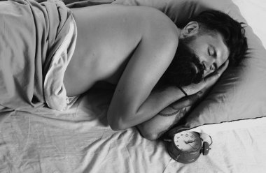 Adam yatakta yatıyor ve uyuyor. Adam sakallı hipster uyku ile ilgili sorunlar yaşıyor. Yatak odasında yatakta uyuyan sakallı adam. Alarm konsepti