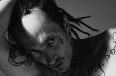 Ciddi yüzlü hippi portresi. Dövmeli hippi adam.