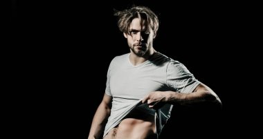 Karanlık arka planda seksi, genç, çıplak bir adam. Baştan çıkarıcı gay