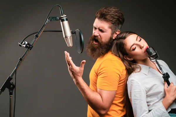 Couple singing. Singer coupl is performing a song with a microphone while recording in a music studio