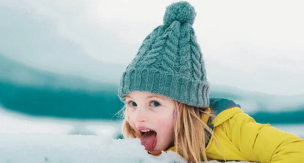 冬の女の子は屋外で雪を食べる 風邪やインフルエンザの概念 舌で雪を舐めなさい 面白い子供たちが — ストック写真