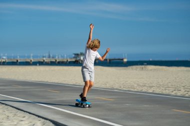 Mutlu aktif çocuk sokakta oynarken kaykayla denge kurmayı öğreniyor. Ata biniyor ve mutlu görünüyor. Çocuk dışarıda sörf ya da kaykay oynuyor.