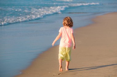 Plajda yaz tatili. Okyanusta oynayan bir çocuk. Çocuklar yaz tatilinde deniz kenarında