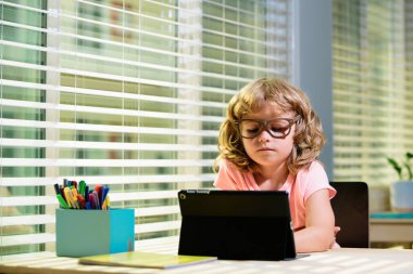 İnternetteki çocuk, evde eğitim görmüş. Mesafe öğrenme. Çevrimiçi e-öğrenim sistemi üzerinden bilgisayar tableti kullanan neşeli küçük çocuk